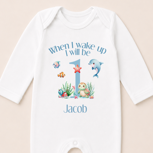 A white onesie with a personalized message and illustrations of marine animals, including a dolphin, starfish, and fish, printed on it.