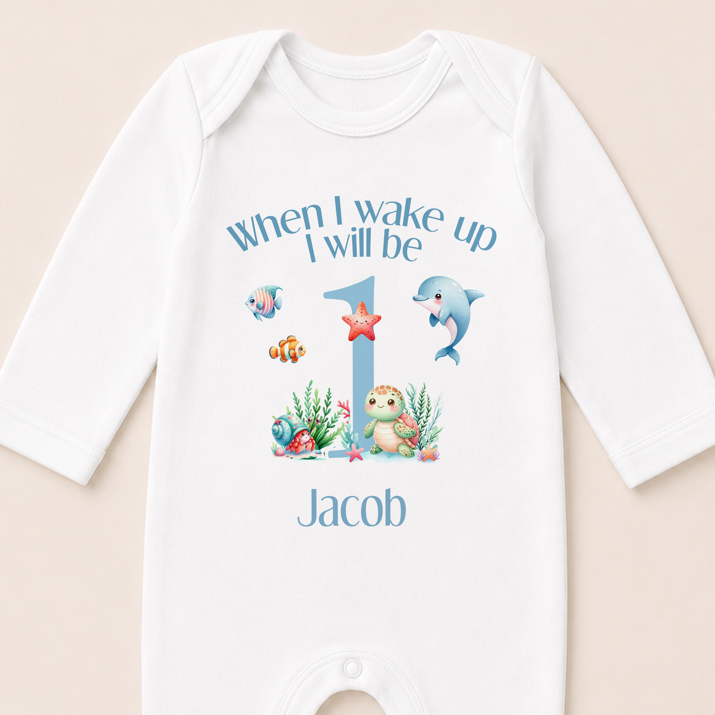 A white onesie with a personalized message and illustrations of marine animals, including a dolphin, starfish, and fish, printed on it.