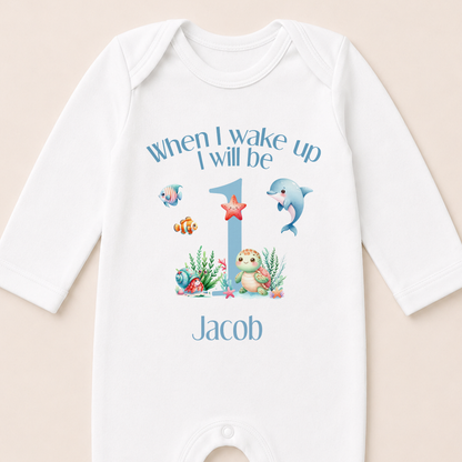 A white onesie with a personalized message and illustrations of marine animals, including a dolphin, starfish, and fish, printed on it.
