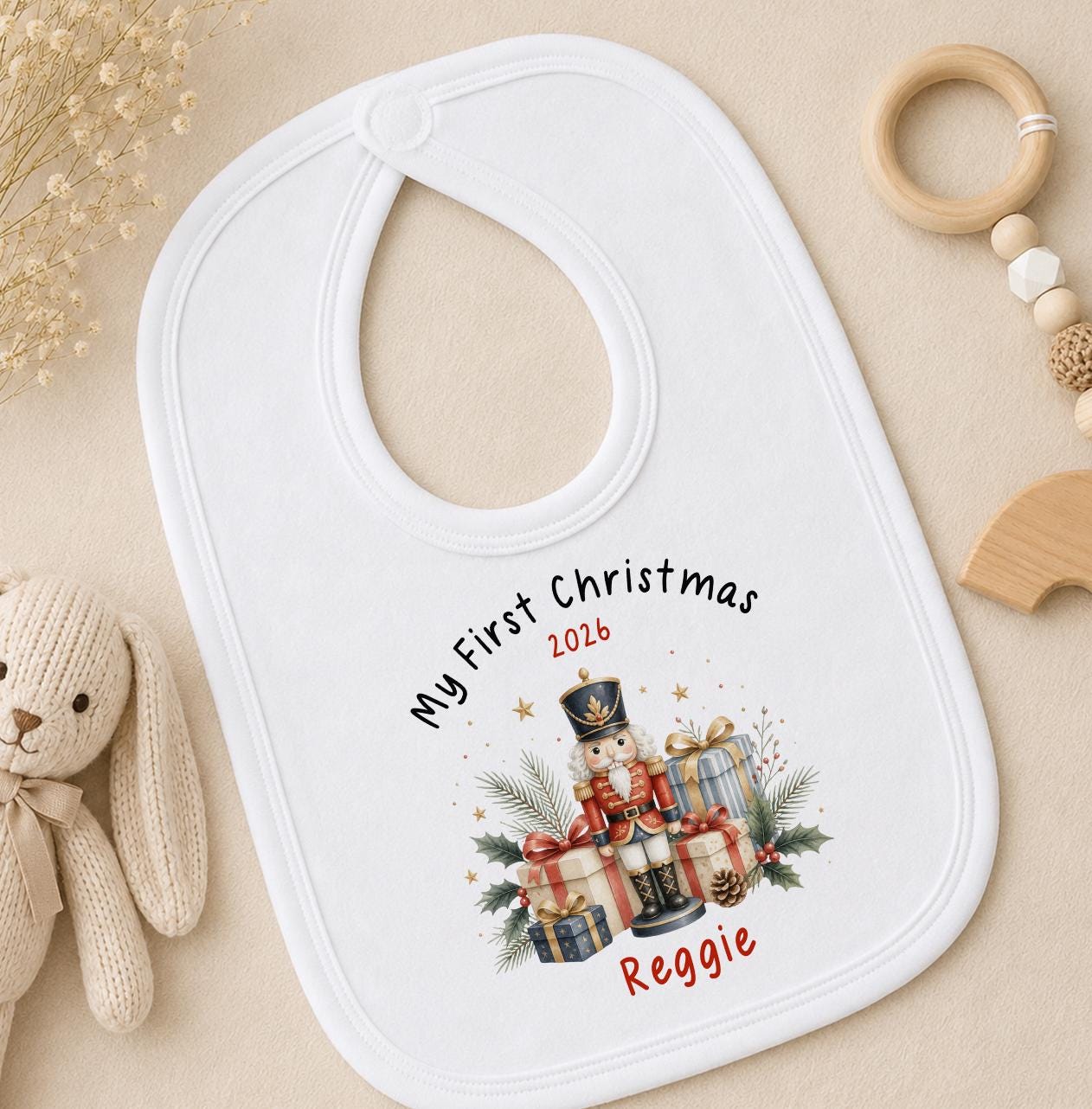 Personalised baby first Christmas bib in white cotton printed with a nutcracker design and baby's name