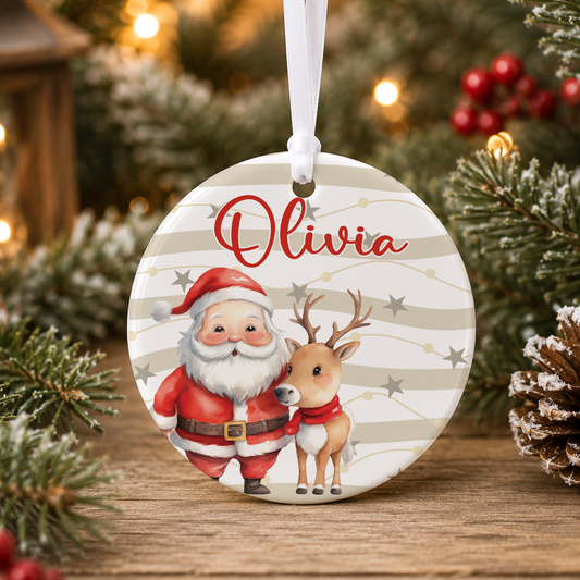 A round ornament featuring a Santa Claus and a reindeer, with the name "Olivia" written on it, hanging on a Christmas tree.