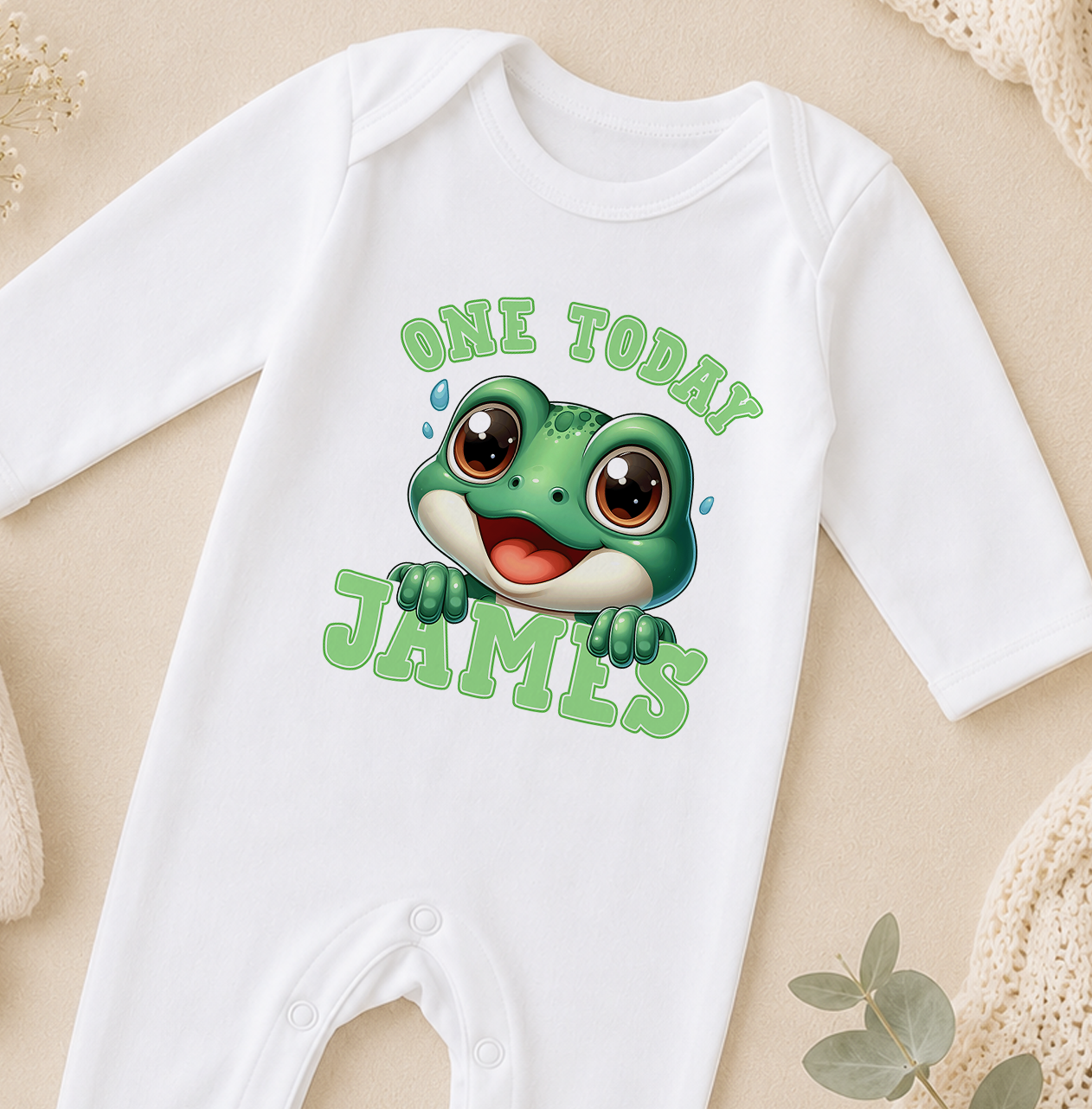White baby onesie featuring a bold green frog illustration and the personalised text 'One Today James'.
