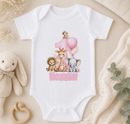 White baby onesie personalised with a pink number one, giraffe, lion and elephant illustrations and the sample name 'Ronnie'