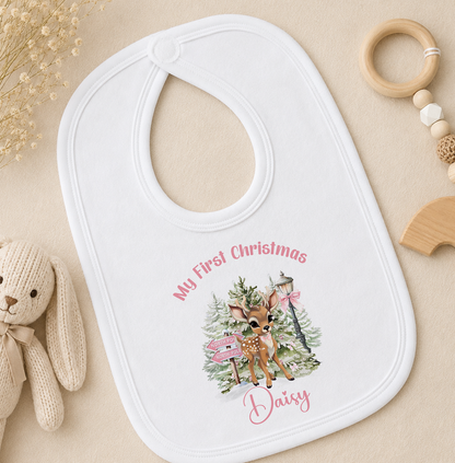 A white baby bib with a personalized design featuring a deer and Christmas trees, along with the text "My First Christmas Daisy".