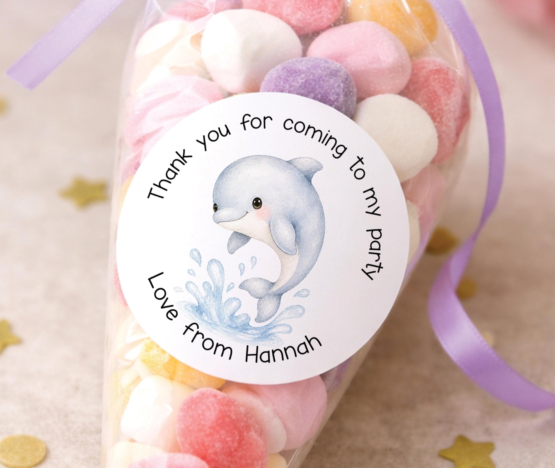 Personalised round dolphin stickers printed with a child's name, showing an ocean-themed design for party bags and favours.