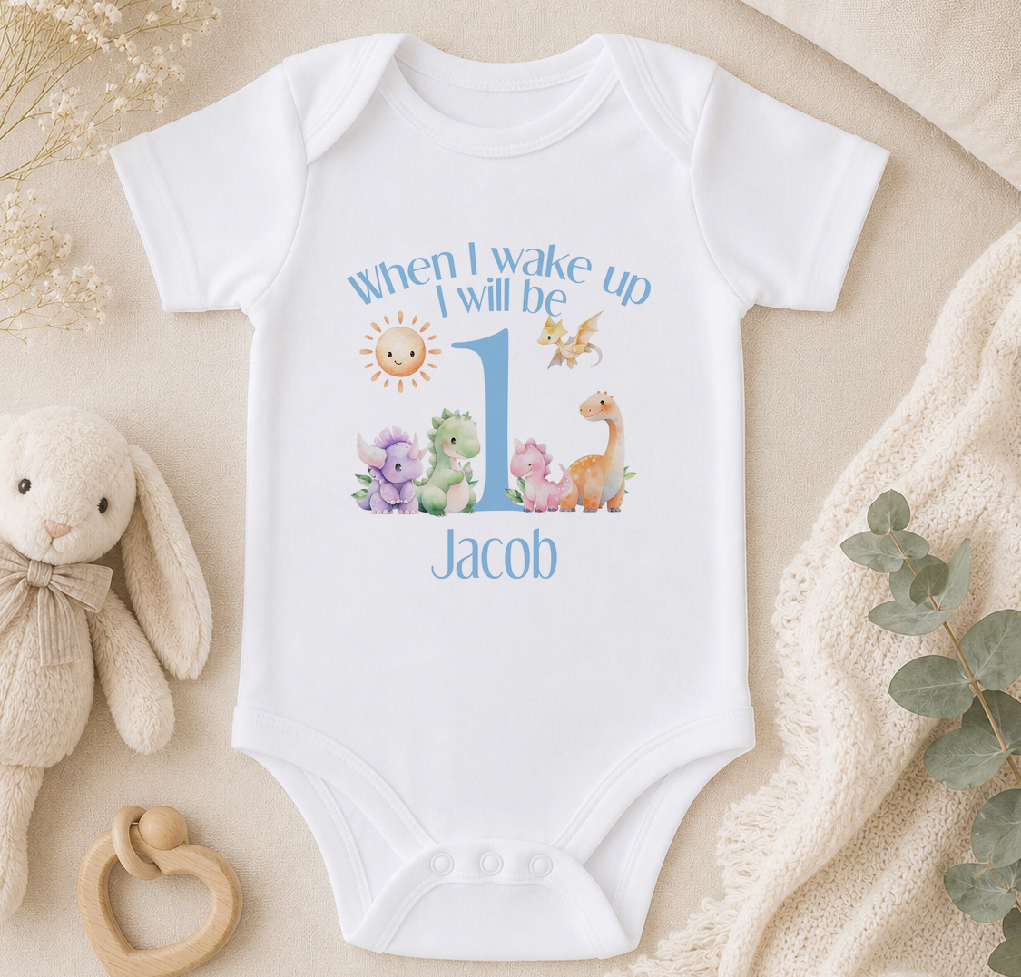 A white onesie with a personalized message and illustrations of various animals, including a bunny, a giraffe, and a dragon, is displayed alongside a stuffed animal and some greenery.