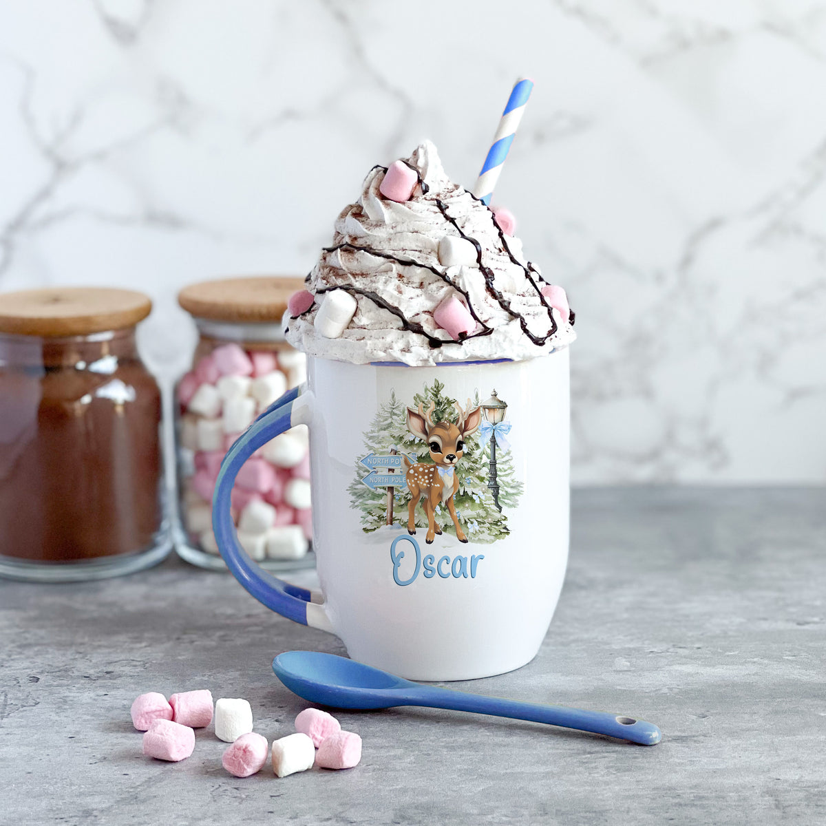 Blue ceramic Christmas mug personalised with a custom name, featuring a festive reindeer design and a spoon built into the handle