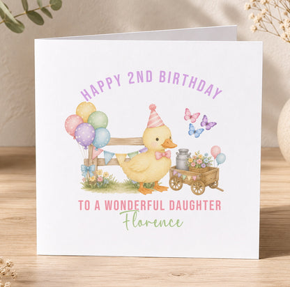 A personalised birthday card featuring a yellow duck wearing a party hat, surrounded by colourful balloons, flowers and a wagon, with the message 'Happy 2nd Birthday to a wonderful daughter Florence'.