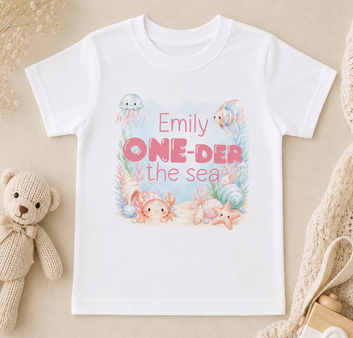 White T-shirt printed with jellyfish, fish and starfish and the personalised phrase 'Emily ONE-DER the sea'