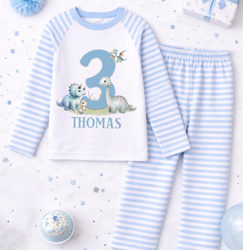 Close-up of the dinosaur motif, personalised name and age printed on the blue stripe pyjama top