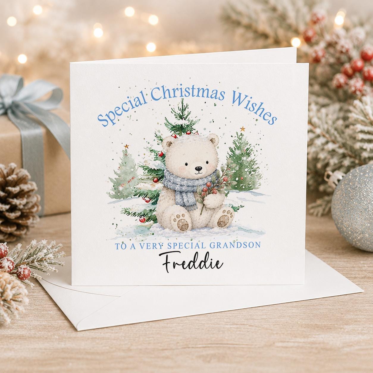 Personalised polar bear Christmas card, white 6x6 inch square card printed with a polar bear cub between snowy trees and a name