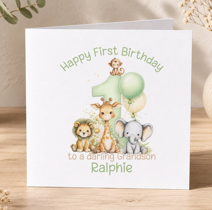 Personalised first birthday card featuring a cartoon lion, giraffe and elephant beside a green number 1, reading Happy First Birthday to a lovely Grandson Ralphie.