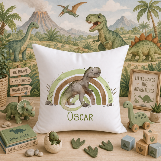 White cushion printed with a watercolour T-Rex dinosaur inside a green and brown rainbow, personalised with the name Oscar, displayed against a dinosaur-themed nursery backdrop with toy dinosaurs and wooden blocks