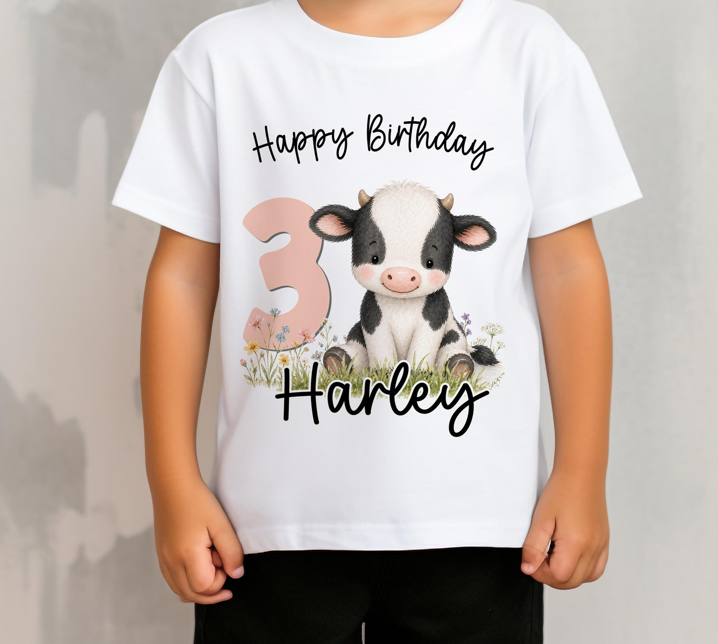 Children's personalised cow birthday t-shirt laid flat, showing the cow design printed with the child's name and age