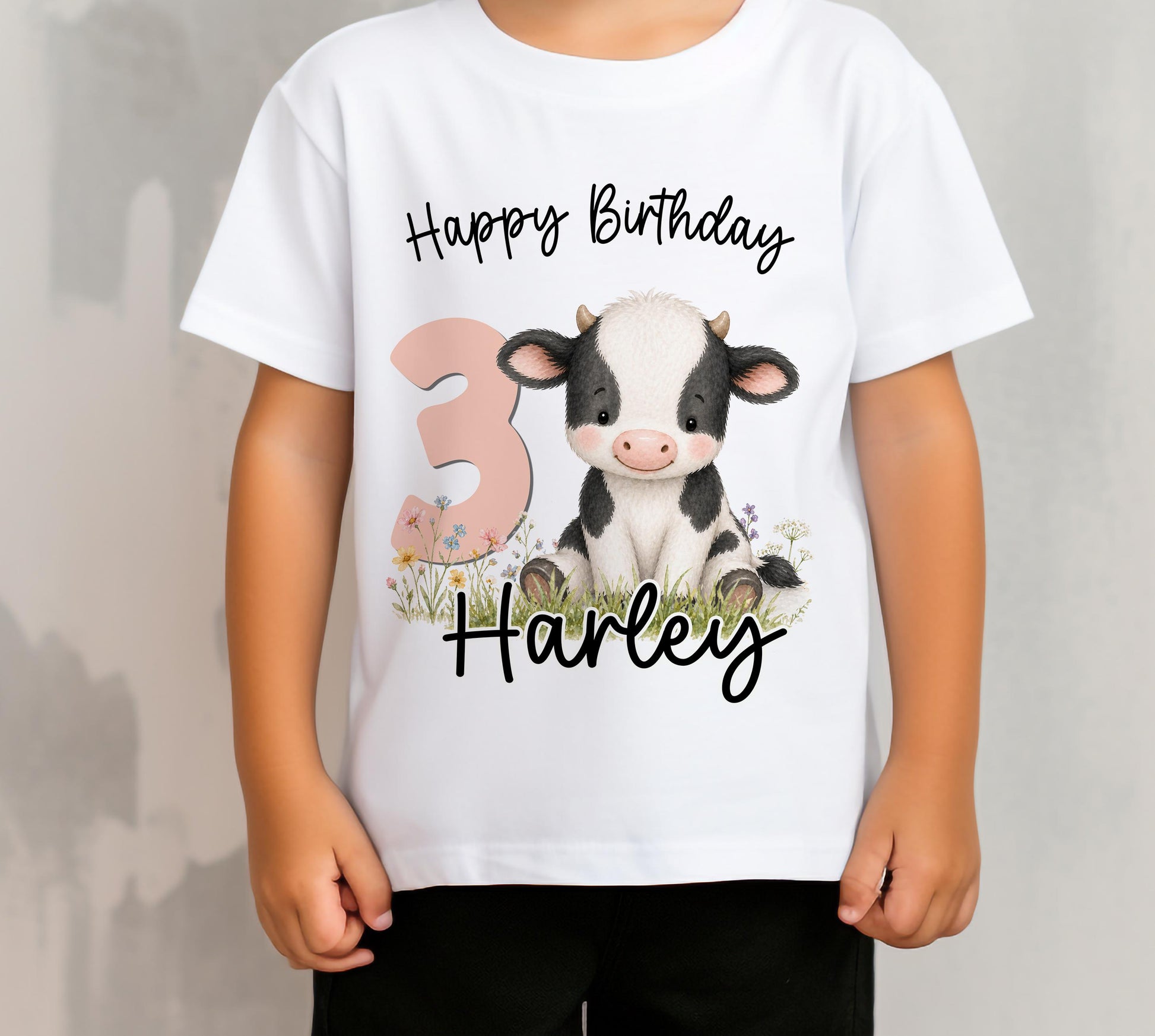 Children's personalised cow birthday t-shirt laid flat, showing the cow design printed with the child's name and age