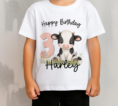 Children's personalised cow birthday t-shirt laid flat, showing the cow design printed with the child's name and age