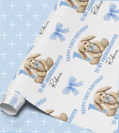 a roll of wrapping paper with a repeating pattern of a teddy bear and the text "Happy First Birthday" and "To My Granddaughter Rebecca".