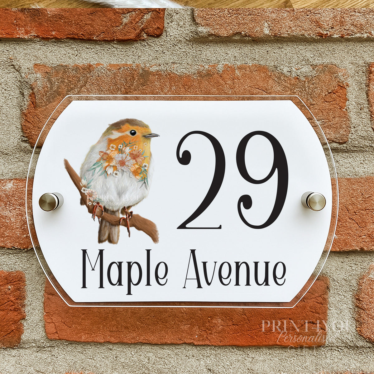 Floral robin house number plaque mounted on a brick wall