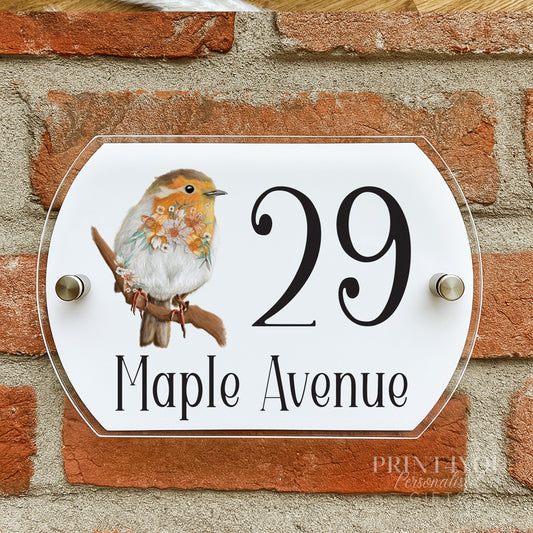 Floral robin house number plaque mounted on a brick wall