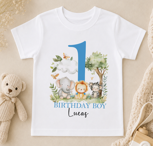 A white t-shirt with a blue number one and illustrations of various animals, including an elephant, lion, and tiger, along with the text "BIRTHDAY BOY Lucas".