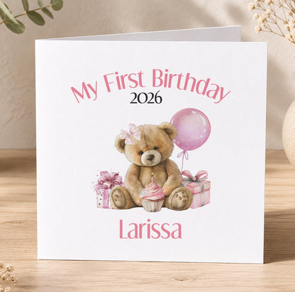 White first birthday card with a teddy bear, a balloon and presents, personalised with the year and the child's name in pink text