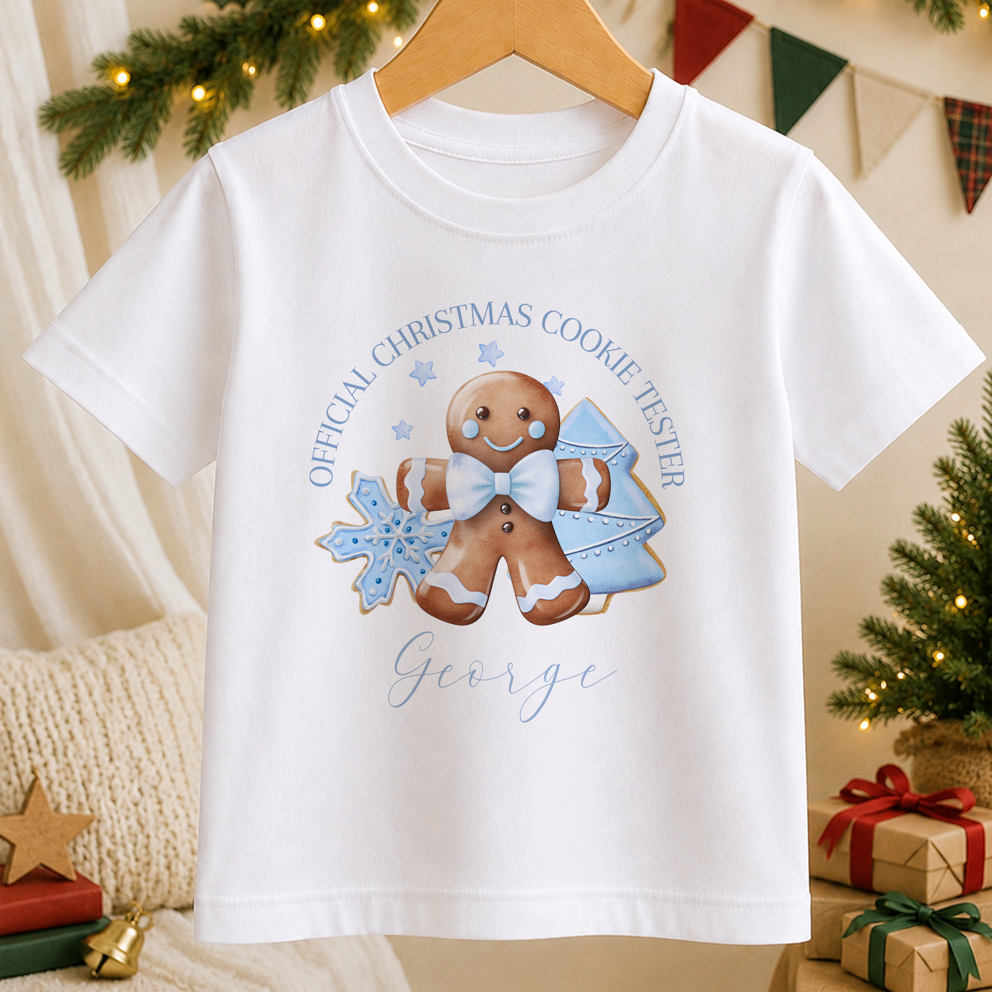 A white t-shirt with a Christmas-themed graphic design featuring a gingerbread man, snowflakes, and a Christmas tree.