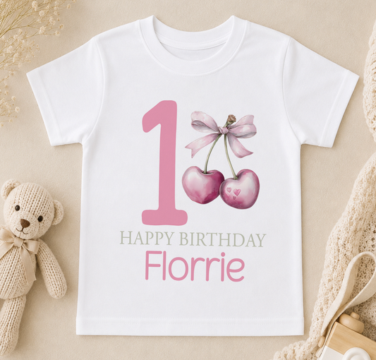 A white t-shirt with a pink number one and heart design, along with the text "Happy Birthday Florrie" printed on it.
