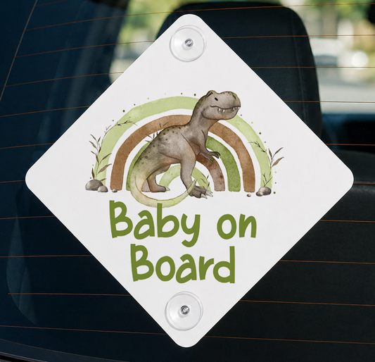 A white diamond-shaped sign with a cartoon dinosaur and a rainbow graphic, mounted on a car window.