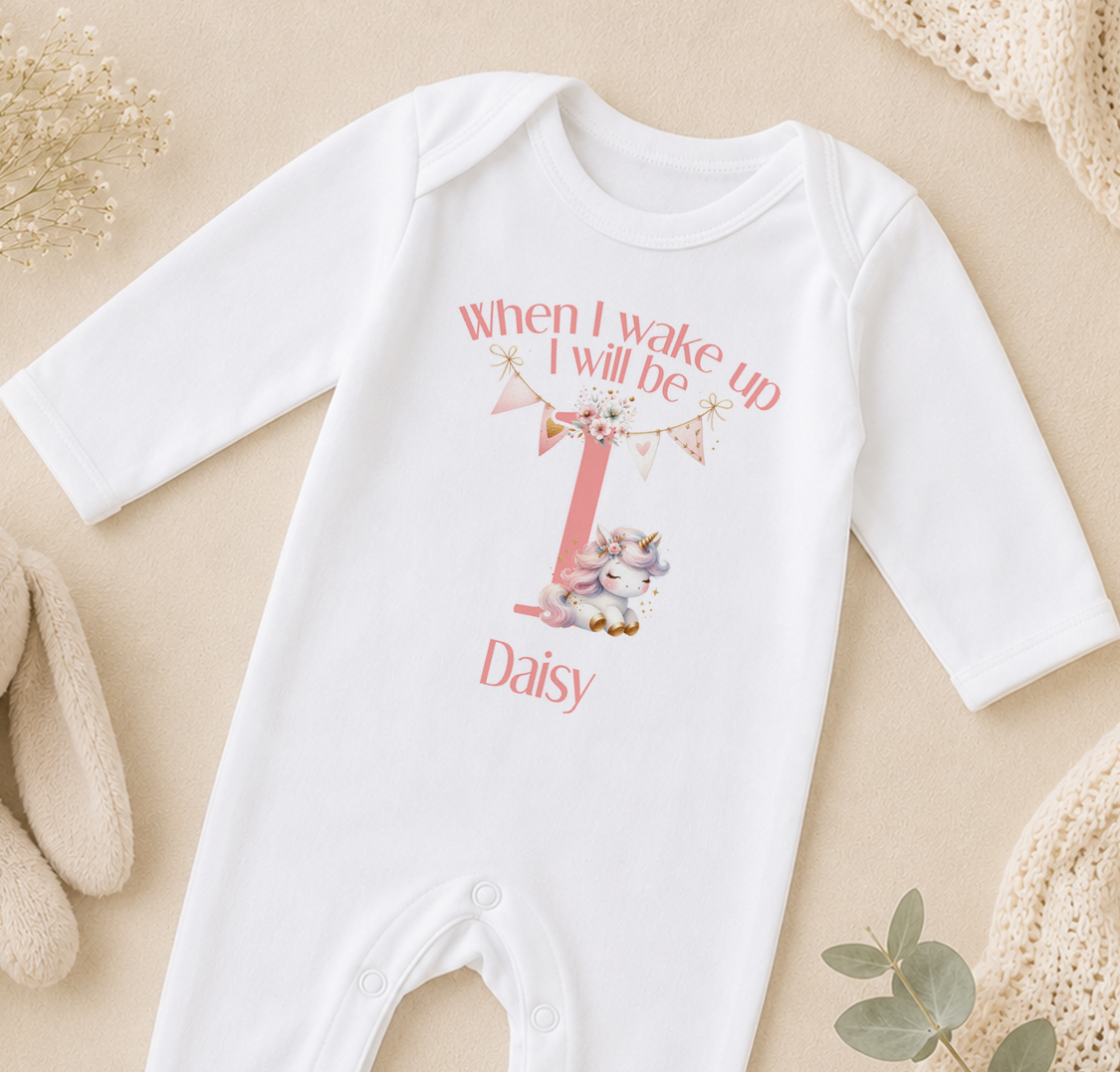 A white onesie with a personalized text and a unicorn graphic, likely for a baby's first birthday.