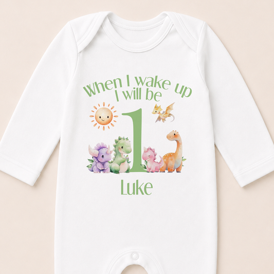 A white onesie with a personalized message and illustrations of various animals, including a sun, dragon, and dinosaur, printed on it.