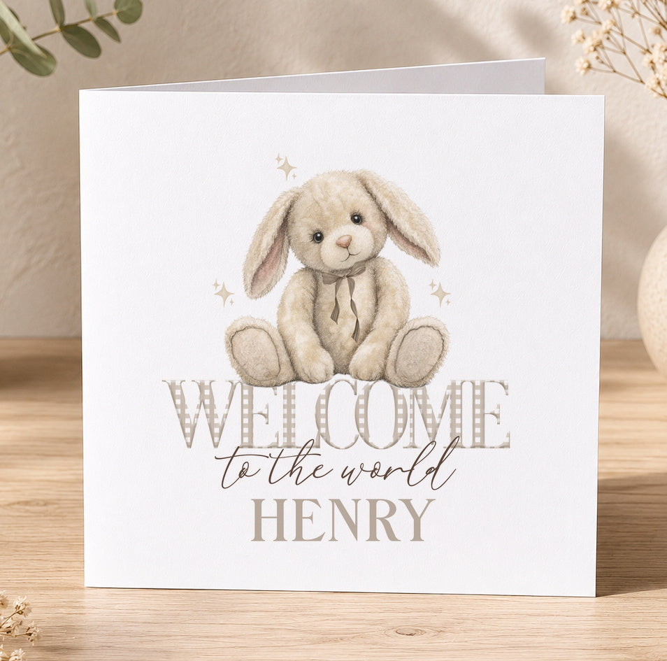 White greeting card illustrated with a stuffed bunny rabbit and the personalised text 'Welcome to the world Henry'.