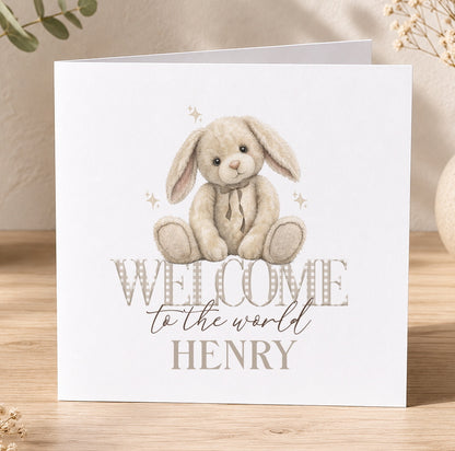 White greeting card illustrated with a stuffed bunny rabbit and the personalised text 'Welcome to the world Henry'.