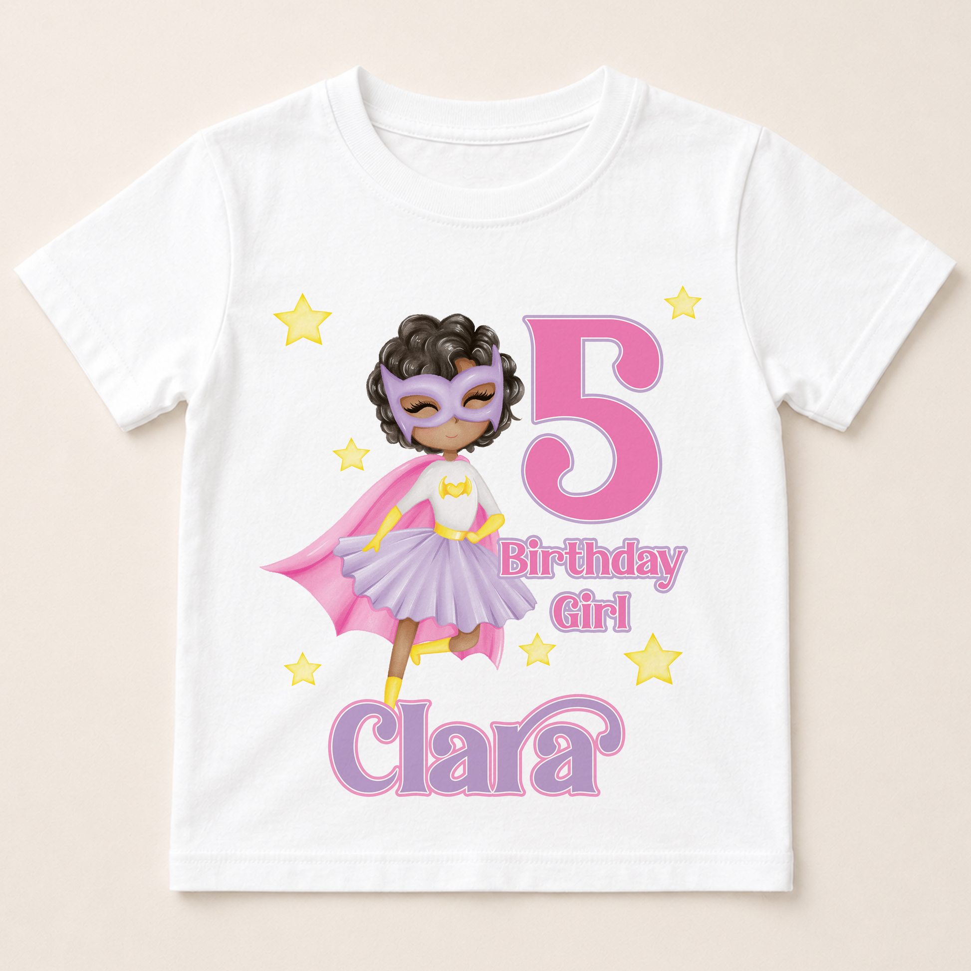 A white t-shirt with a graphic design featuring a young girl wearing a superhero costume, surrounded by stars and the number 5.