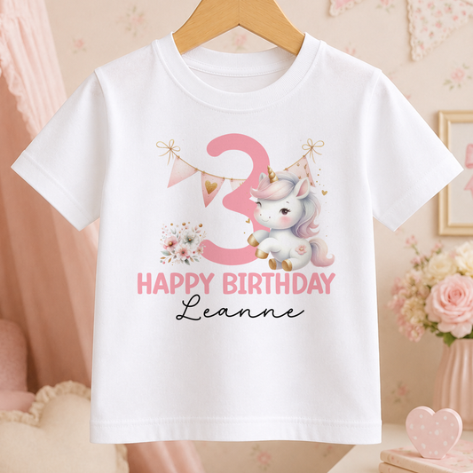 White cotton t-shirt printed with a pink unicorn, a large age number and personalised name