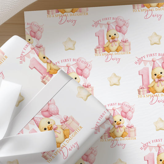 Close-up of personalised first birthday gift wrap with a cute duckling, pink balloons, number one and presents on premium white wrapping paper.