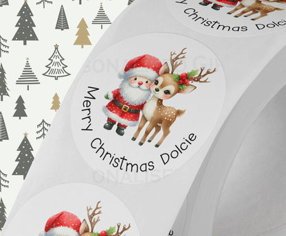 Personalised Santa and reindeer Christmas sticker in white gloss finish, custom name printed on a strip of round gift labels