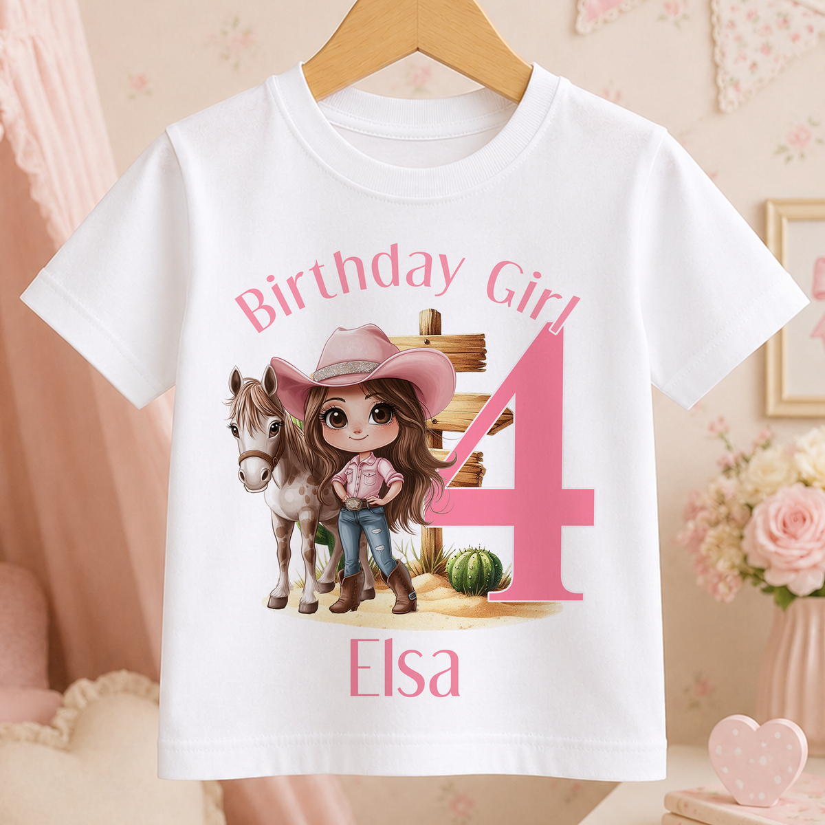 A white t-shirt with a cartoon image of a girl wearing a cowboy hat and standing next to a horse, along with the text "Birthday Girl 4" and "Elisa".