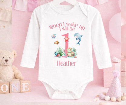 Personalised first birthday pyjamas laid flat to show the printed name.