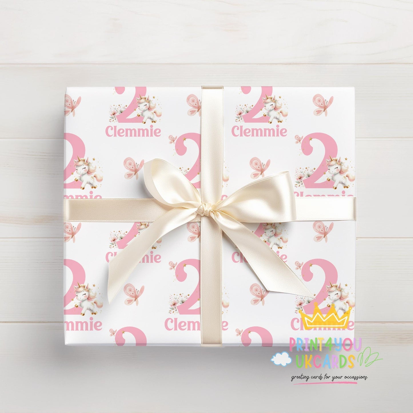 A gift box wrapped in personalised pink and white wrapping paper printed with the name 'Clemmie', tied with a white ribbon