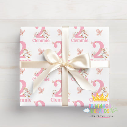 A gift box wrapped in personalised pink and white wrapping paper printed with the name 'Clemmie', tied with a white ribbon