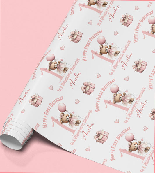 a roll of wrapping paper with a repeating pattern of a teddy bear and a gift box, along with the text "Happy First Birthday" and "Amanda" printed on it.