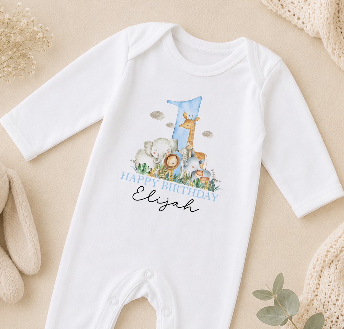 A white onesie with a printed image of various animals, including a giraffe, elephants, and a lion, along with the text "Happy Birthday Elijah".