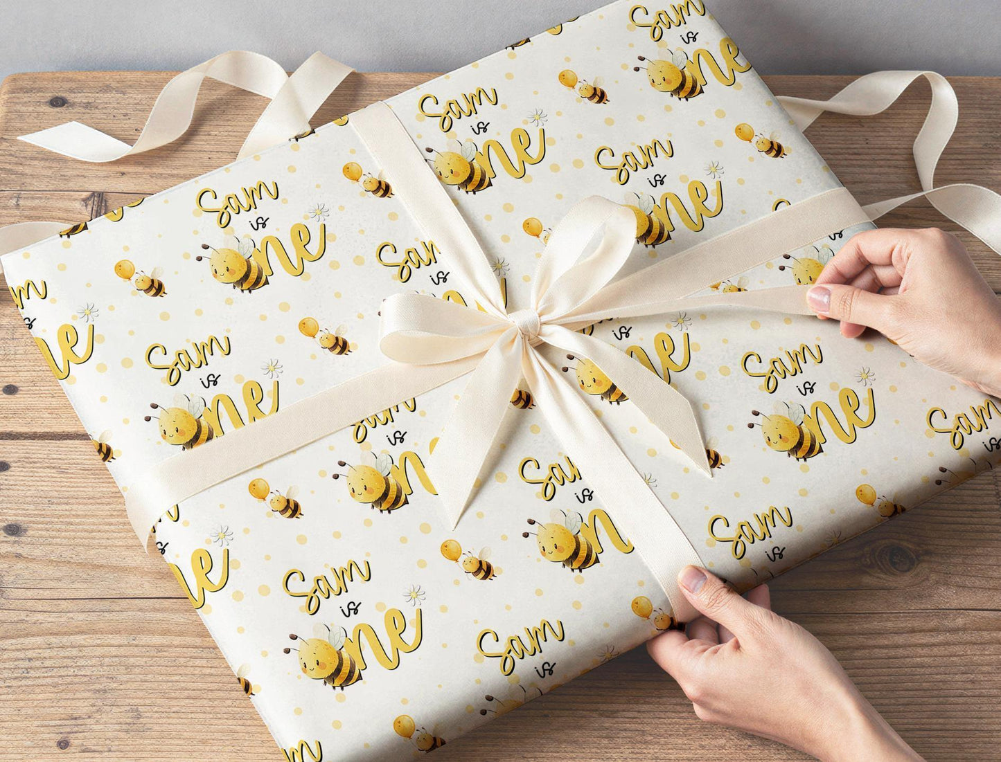Personalised bee first birthday wrapping paper with cute honey bee design and custom name for a boy or girl turning one.
