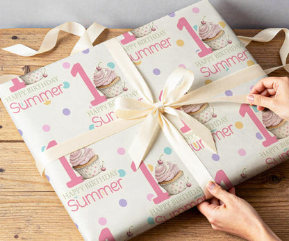 Close-up of hands wrapping a present in the personalised pink cupcake and confetti dot wrapping paper with white ribbon