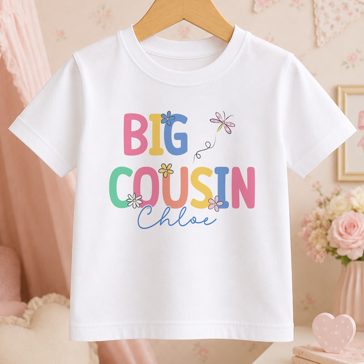 A white t-shirt with the text "BIG COUSIN Chloe" printed on it, along with colorful flowers.