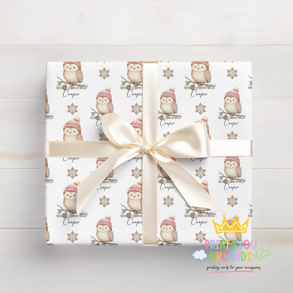 Gift wrapped in owl and snowflake Christmas paper viewed from above, tied with a cream bow.