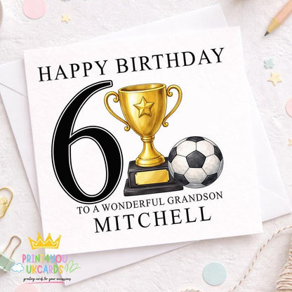 White square birthday card reading 'Happy Birthday 6, To A Wonderful Grandson, Mitchell', illustrated with a gold trophy topped with a star and a black-and-white football, standing on a wooden surface with confetti and a pencil