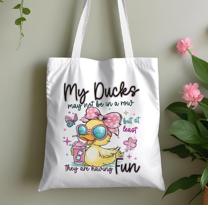 White cotton tote bag printed with a cheeky cartoon duck design, laid flat against a plain background