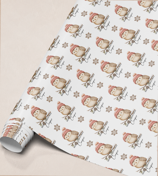 Close-up of rolled owl and snowflake Christmas wrapping paper showing the repeating pattern with the personalised name Cooper.