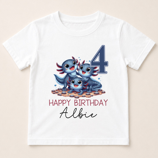 A white t-shirt with a graphic design featuring three cartoon axolotls, which are a type of salamander, and the number 4. The text below the design reads "Happy Birthday Albie".